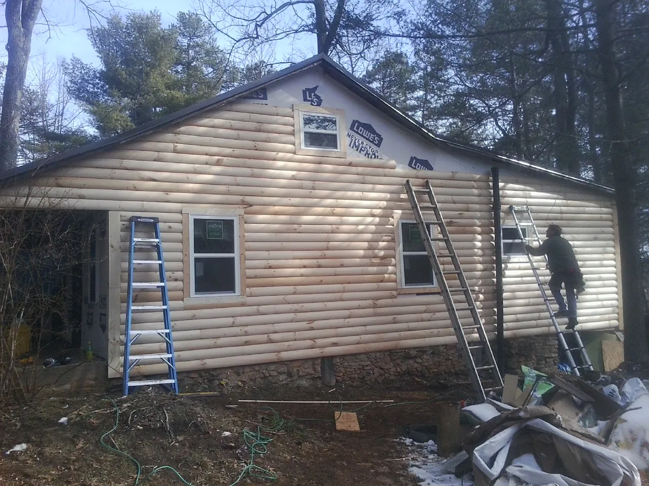 Ladders set against fresh log siding during an exterior remodel in Topeka