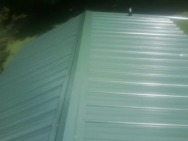 New green metal panels meeting at the ridge of a roof — Flat Roof Repair work by our crew in Topeka
