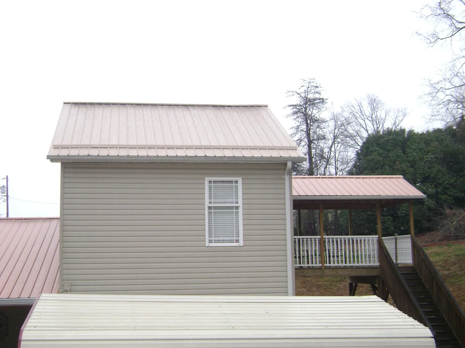 Tan metal roofs on a two story addition and attached porch, from a Roof Replacement job in Topeka